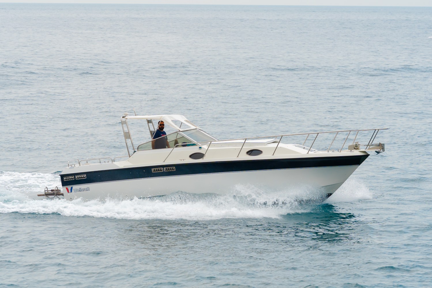 Motorboat with person cruising on calm sea.
