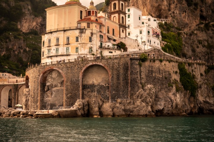 Historic building on a rocky coastline under a cloudy sky.
