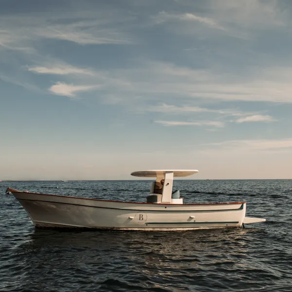 A solitary motorboat floating on a calm sea under a cloudy sky.