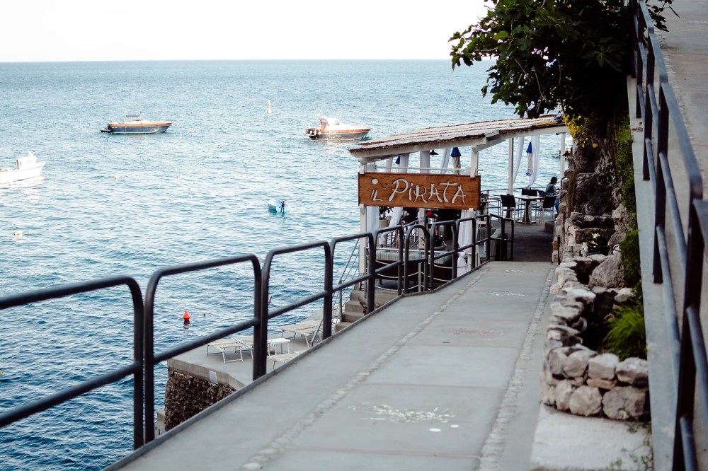 Coastal restaurant 'Il Pirata' with oceanview and boats in the distance.