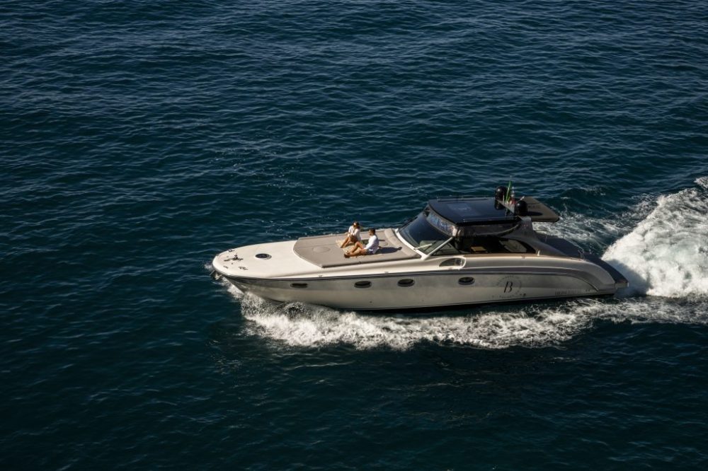 A luxury yacht with a person relaxing on the deck, cruising through blue ocean waters.