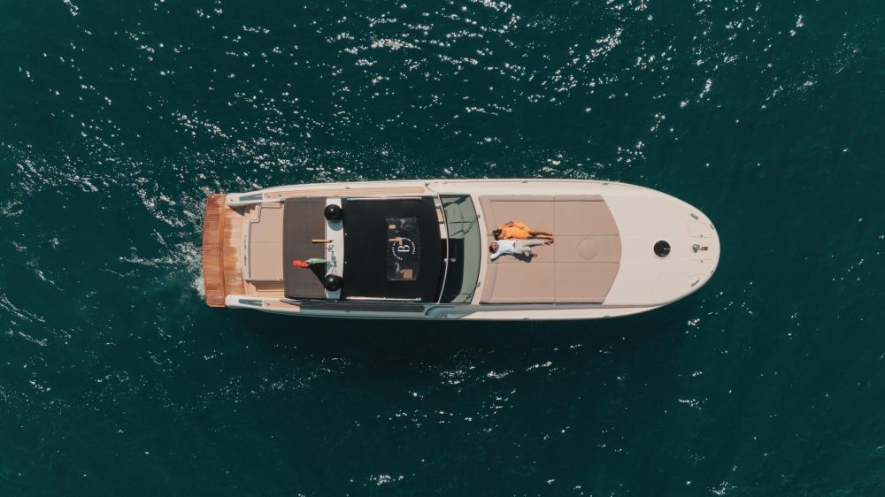 Aerial view of a boat on the water with two people sunbathing on deck.