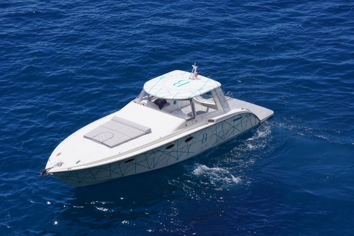 White motorboat cruising on calm, deep blue water.